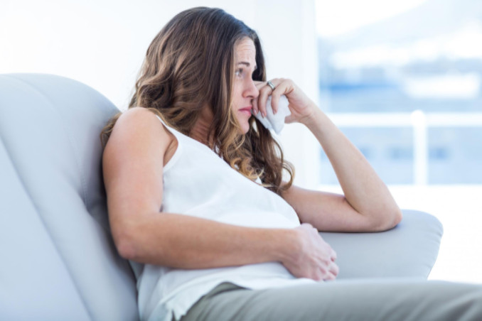 Upset young woman on couch: All About Women Pregnancy & Prenatal Care Blog
